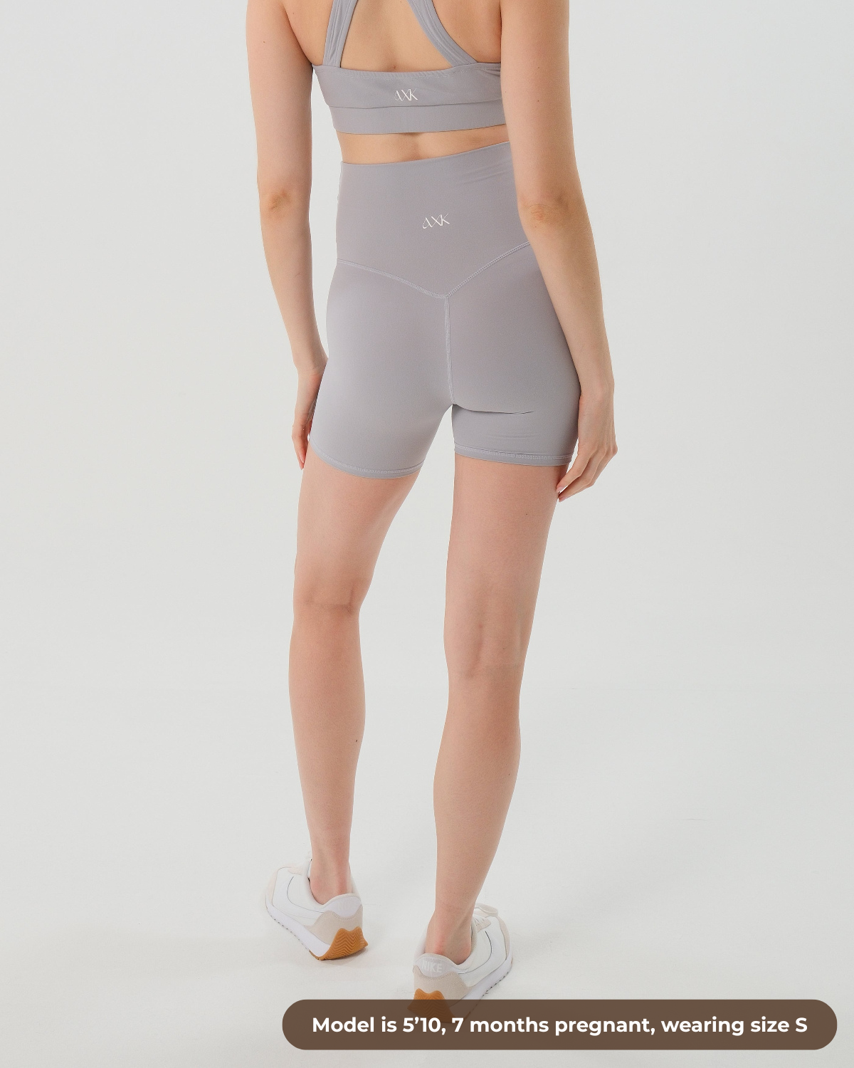 Pregnant woman wearing premium light grey maternity bike shorts with a supportive high waist and matching high-impact, racerback maternity and nursing sports bra. Best reviewed premium maternity athletic and activewear by AXK, petite and tall friendly, in regular and plus size options.