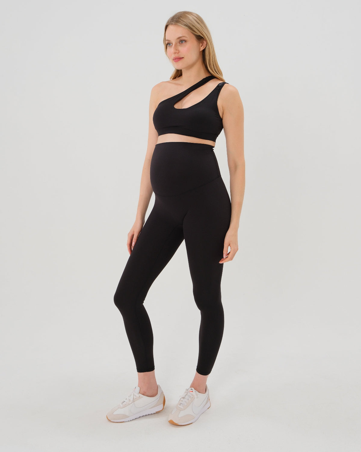 Pregnant woman wearing our best reviewed AXK premium black maternity leggings for 2026 with a matching trendy one shoulder nursing sports bra. Premium maternity athletic and activewear by AXK, available in plus sizes. Petite and tall friendly.