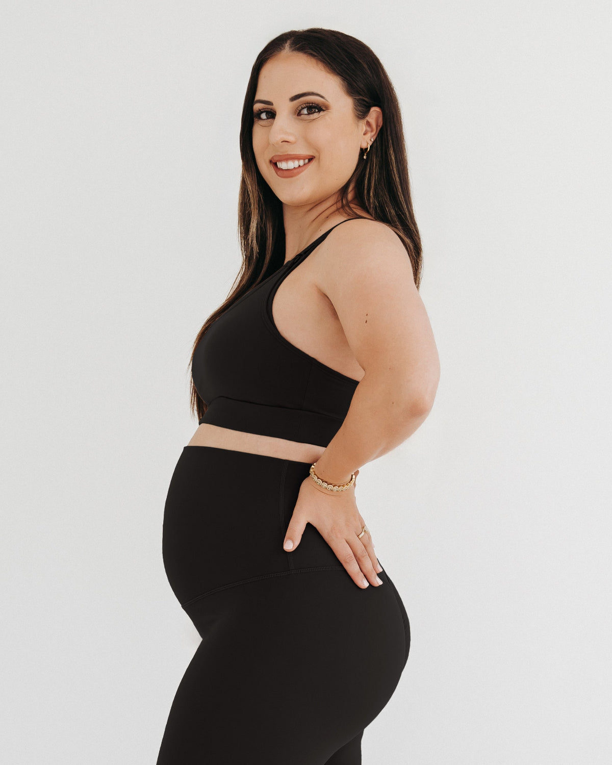 Pregnant woman wearing a black high-impact, racerback, maternity and nursing sports bra with one-handed clip access. 2026 premium best selling maternity athletic and activewear by AXK, petite and tall friendly, standard and plus sizes.