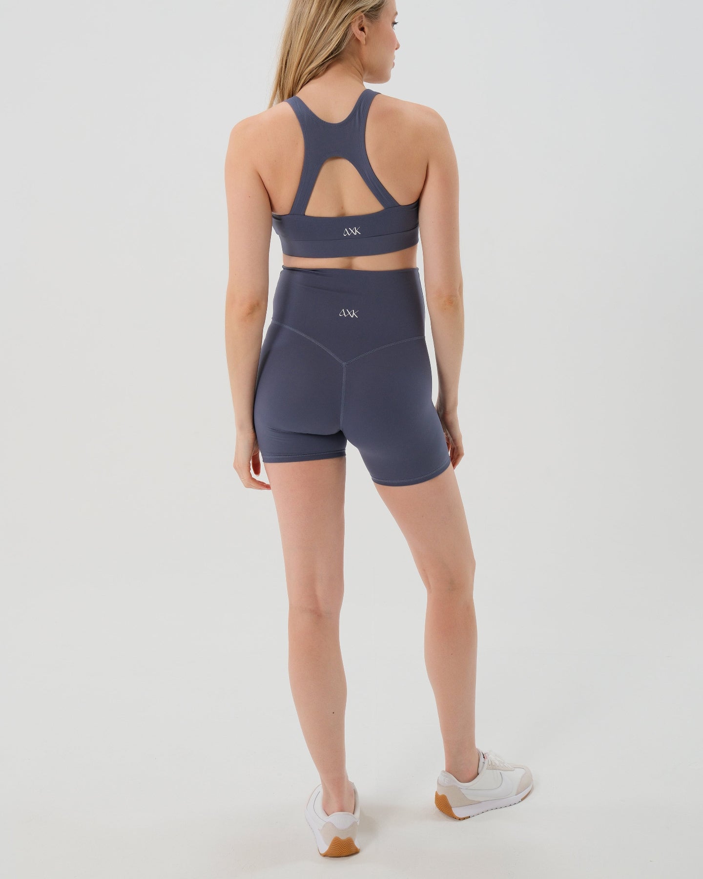 Pregnant woman wearing premium blue maternity bike shorts with a supportive high waist and matching high-impact, racerback maternity and nursing sports bra. Best reviewed 2026 premium maternity athletic and activewear by AXK, petite and tall friendly, in regular and plus size options.