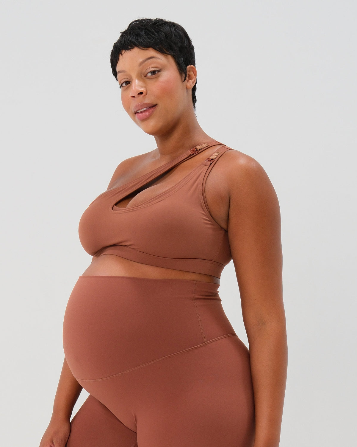 Brown one-shoulder maternity and nursing sports bra and matching leggings. The bra features one-handed clip access for easy breastfeeding. Premium maternity activewear by AXK is offered in petite and plus size.