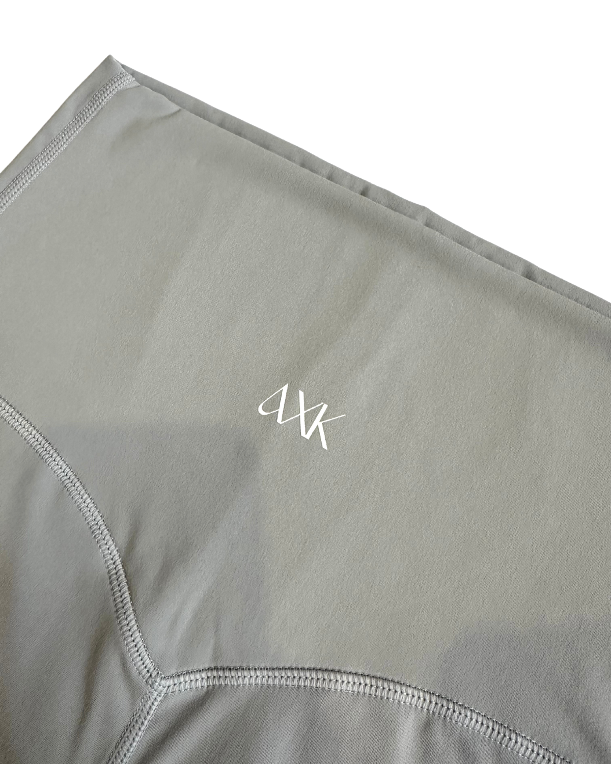 Close-up of premium light grey maternity leggings featuring the AXK logo and flattering V-seam detail, displayed on a white background. Premium maternity athletic and activewear by AXK.