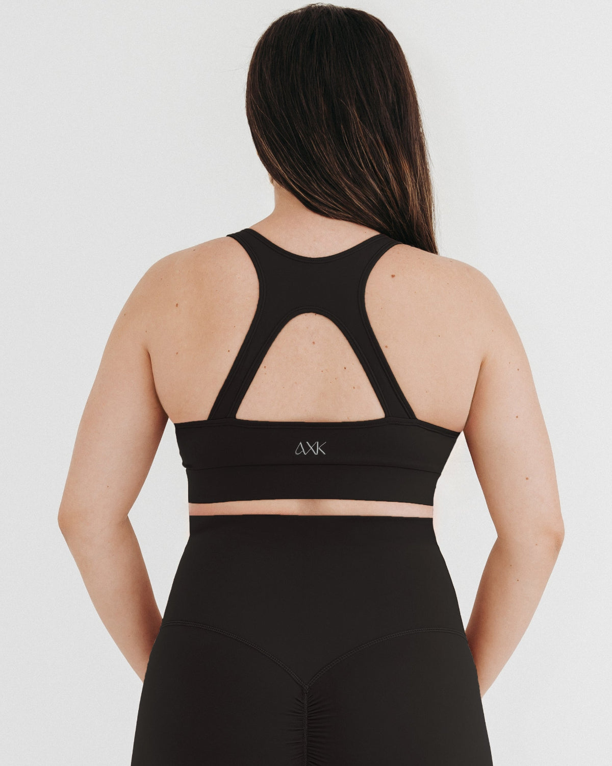 Back view of black AXK high-impact, racerback, maternity and nursing sports bra with one-handed clip access. Premium maternity athletic and activewear by AXK, offered in plus size maternity, tall friendly, and petite maternity sizing.