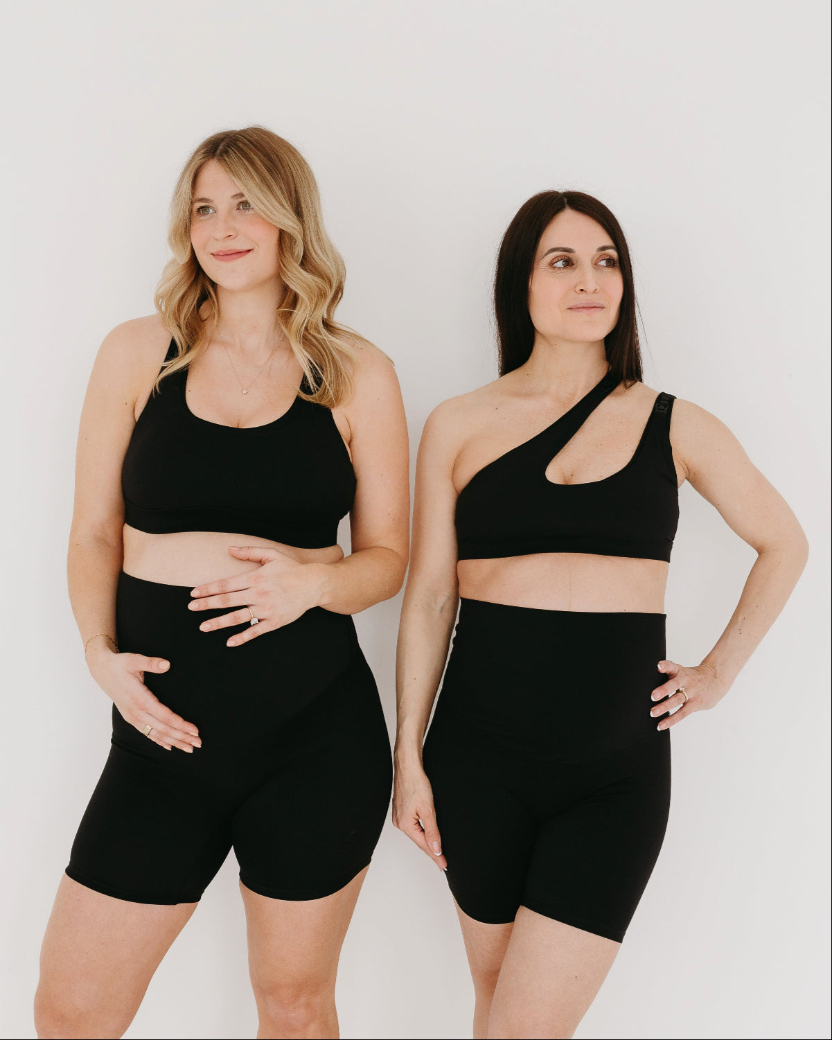 Two pregnant women wearing AXK maternity and nursing sports bras and maternity bike shorts in black. AXK offers premium quality maternity activewear and athleisure fashion. 