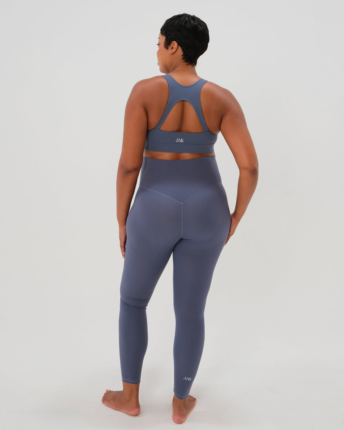 Pregnant woman wearing our best reviewed premium brown maternity leggings for 2026 with a flattering scrunch butt and matching trendy one shoulder nursing sports bra, standing against a white background. Premium maternity athletic and activewear by AXK.