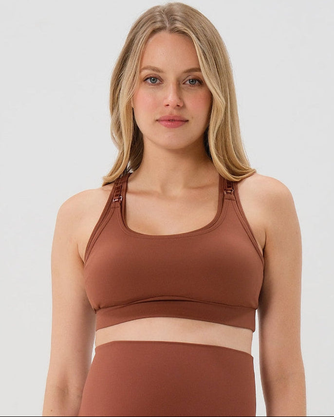 Pregnant woman wearing premium brown maternity bike shorts with a supportive high waist and matching high-impact, racerback maternity and nursing sports bra, standing against a white background. Premium maternity athletic and activewear by AXK - high quality petite, tall, and plus size maternity. 